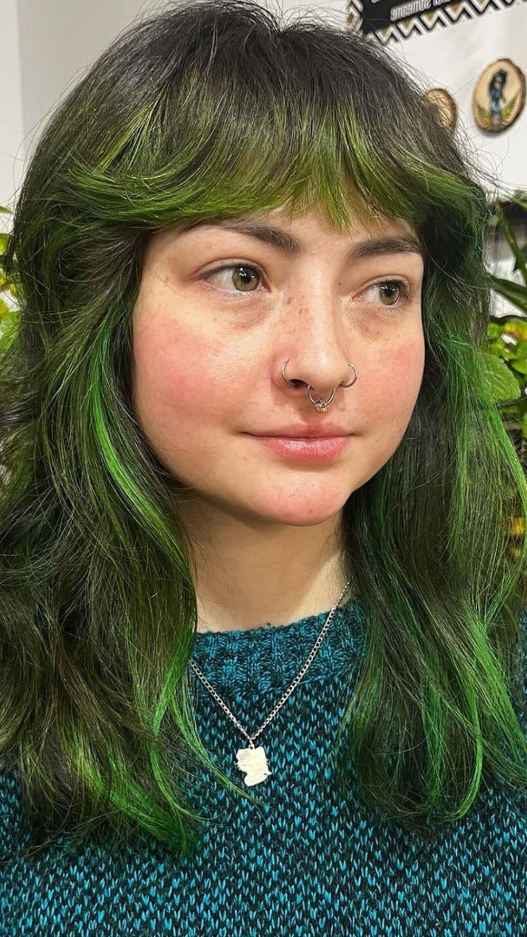 A woman modelling a green shag with brow-length bangs hairstyle.