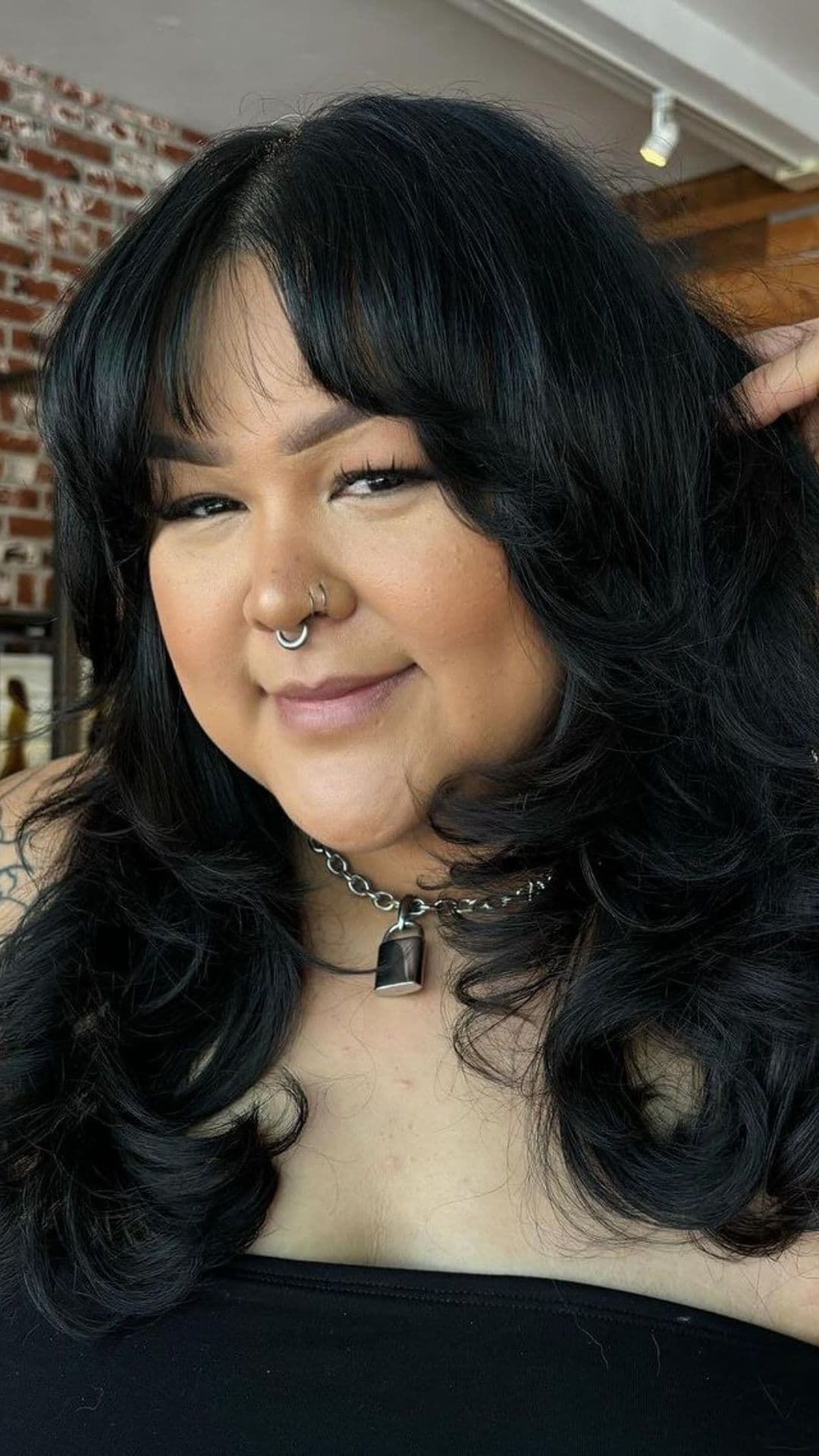 A woman modelling a medium-to-long wavy layered hairstyle.
